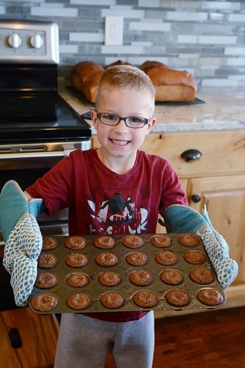 Little boy holding a pan of cooked muffins.