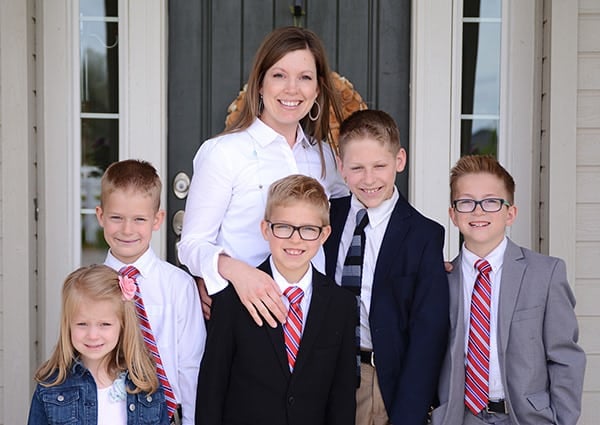 A mother and her five kids standing in front of their house dressed in Sunday best.