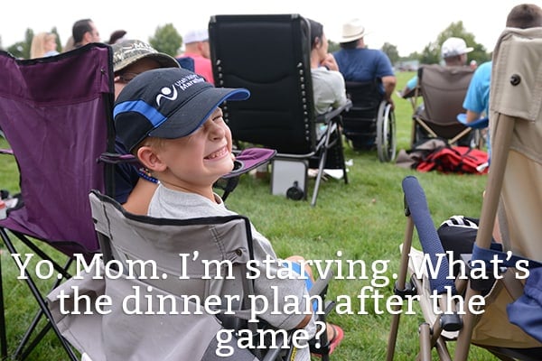 A little boy sitting on a camp chair smiling.
