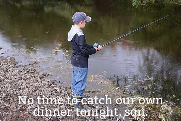 A little boy fishing in a creek.