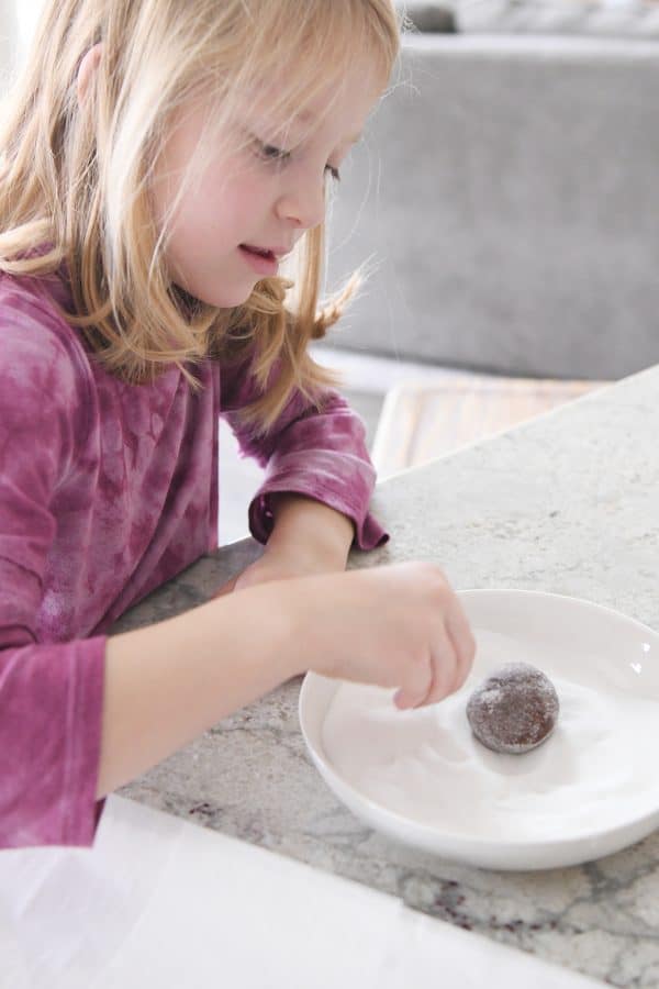 Rolling chocolate cookie in granulated sugar.