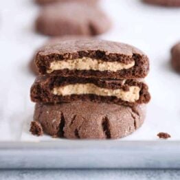 stack of chocolate peanut butter stuffed cookies with top cookie broken in half