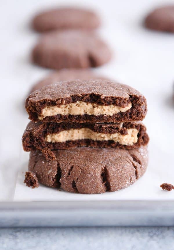 Stack of chocolate peanut butter stuffed cookies with top cookie broken in half.