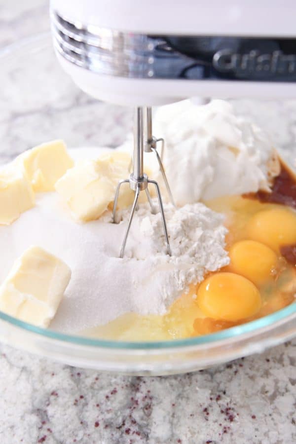 Mixing all the ingredients for chocolate chip cake batter with handheld mixer.