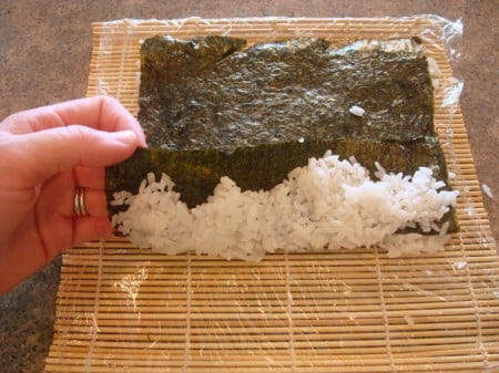 Lifting Up to Show Rice white rice being wrapped up in nori