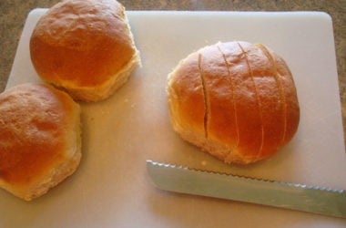 Cutting Bread 4 rolls on a white cutting board being cut into 1/2 inch strips