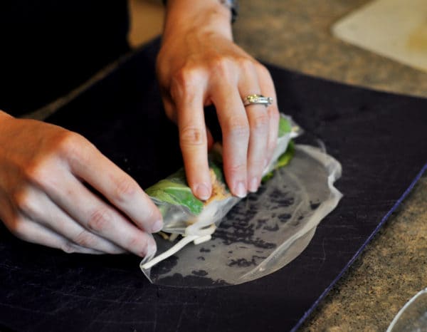 rolling vegetables in a clear rice wrap
