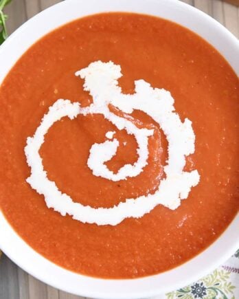 the best classic tomato soup in white bowl with swirl of heavy cream
