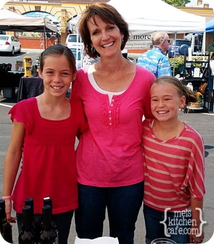 An adult lady standing between two girls.