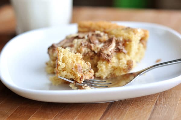 A slice of cake with Heath Bar crushed on top on a white plate.