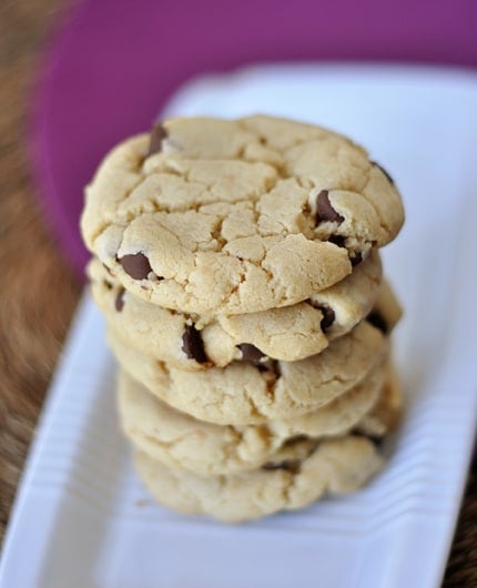 Chocolate chip cookies stacked on top of each other on a white rectangular platter.