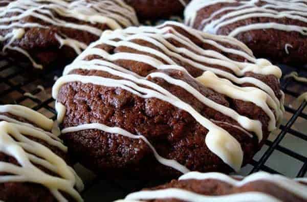 Chocolate brownie bites with white icing drizzled over the top.