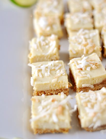 A white platter with small squares of key lime bars topped with toasted coconut.