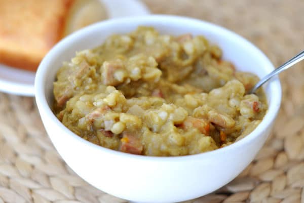 White bowl with thick split pea and ham soup.