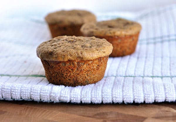 Three cooked bran muffins on a kitchen towel. 