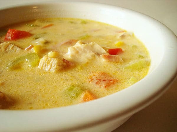 Chicken chowder with corn and chopped peppers in a white bowl.