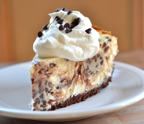 chocolate chip studded cheesecake with chocolate crust and topped with whipped cream and mini chocolate chips