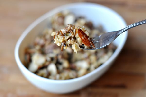 White dish full of cooked wild rice, with a fork taking a bite out.