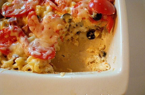 Macaroni cheese bake with a scoop taken out in a white ceramic dish.