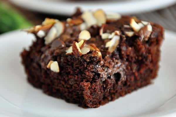 A piece of streusel-topped chocolate zucchini cake on a white plate.