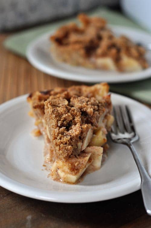 Two slices of apple crumb pie on white plates.