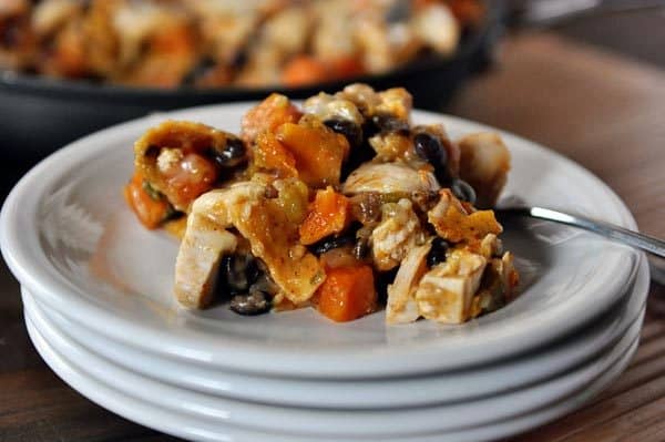 A helping of black bean enchilada chicken casserole on a stack of white plates.