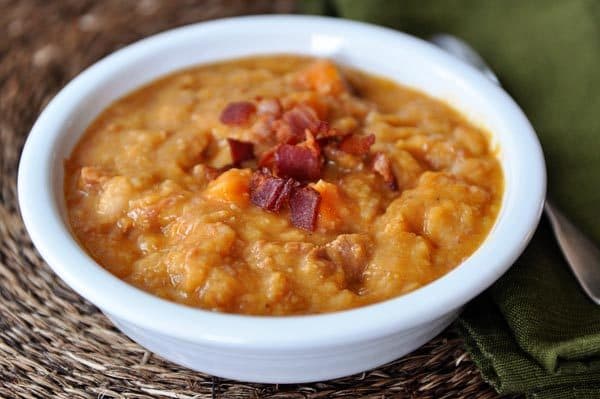 White bowl with ham, sweet potato, bacon, and white bean soup.