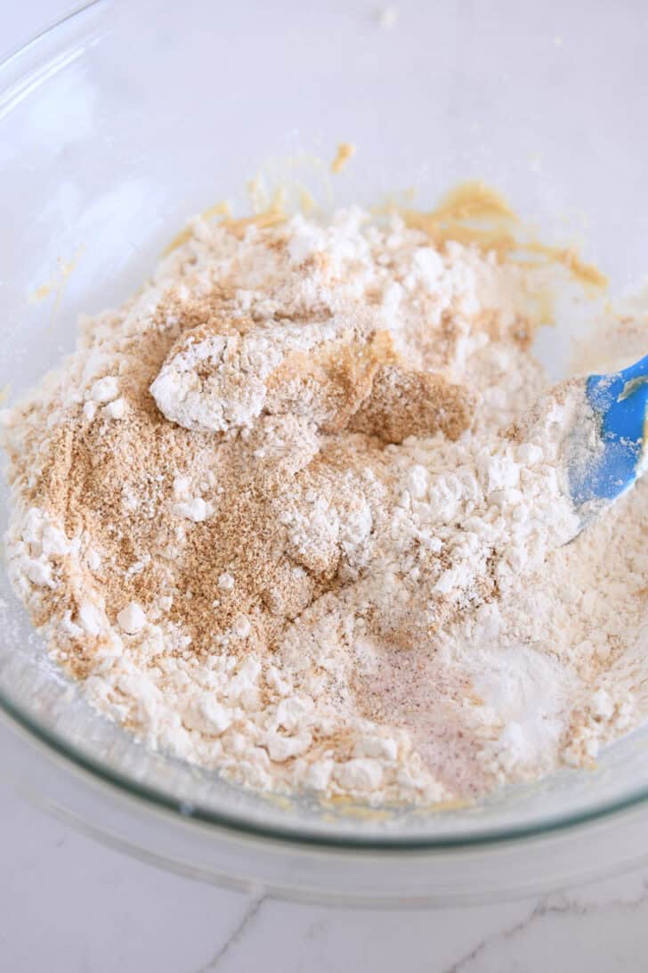 Glass bowl with graham cracker crumbs, flour, salt and baking soda in graham cracker cookie dough.