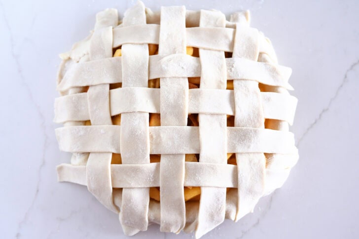 Assembling lattice pie crust on fresh peach pie.