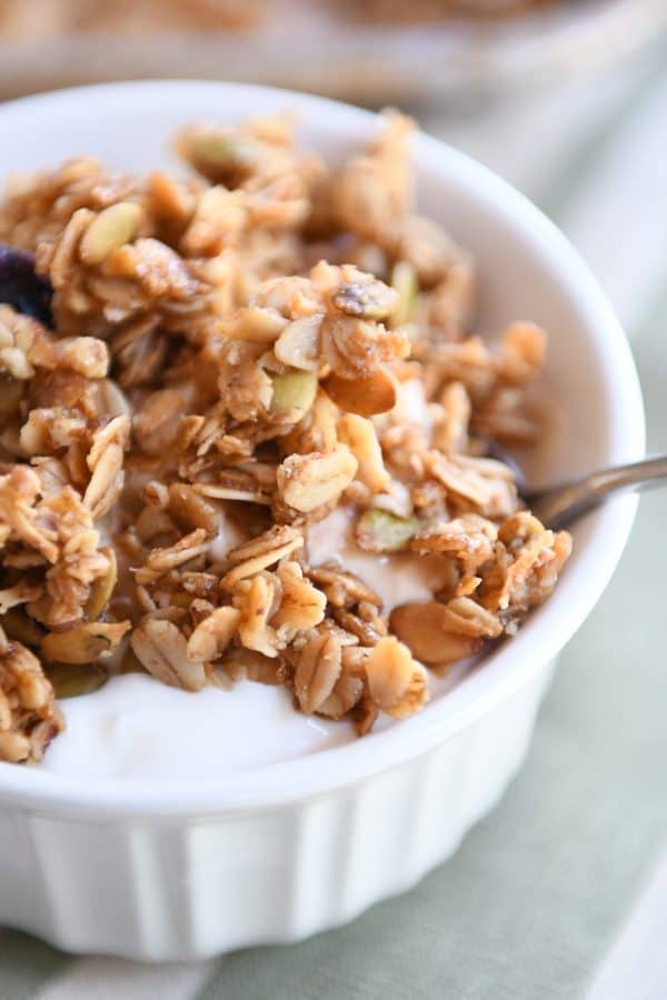 White bowl with yogurt and brown butter pecan granola.
