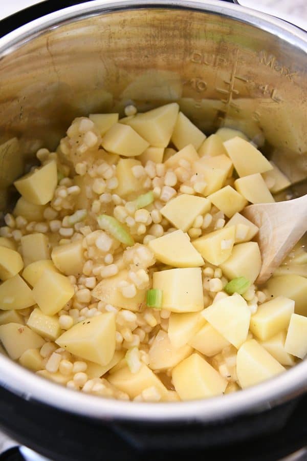 Top down view of instant pot with potatoes and corn added.