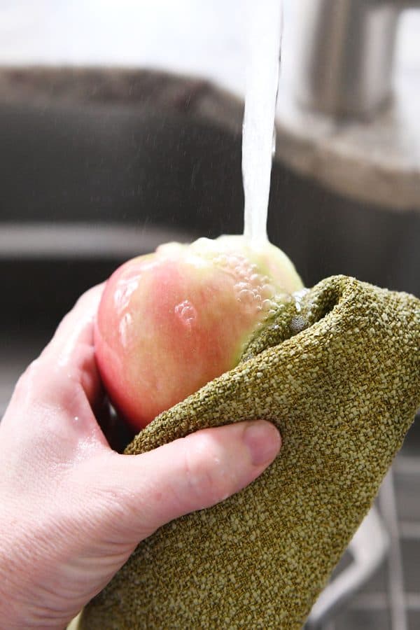 Washing and scrubbing apples with soapy water.