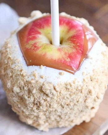 Dipped and decorated homemade caramel apple with white chocolate and graham cracker crumbs.