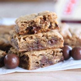 Two malted chocolate chip blondies stacked with half of a blondie on top.