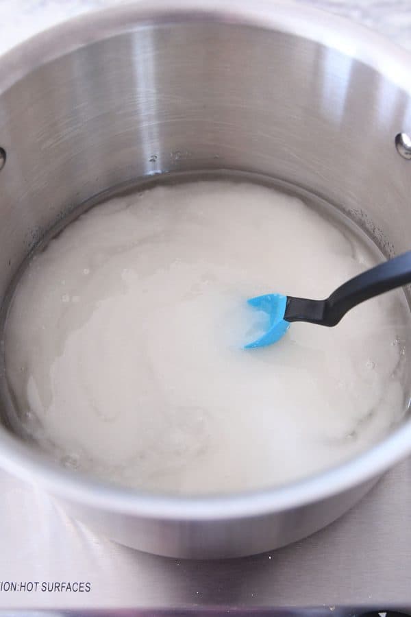 Combining sugar, corn syrup, and water in pot for caramels.