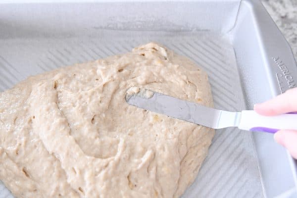Spreading banana coffee cake batter in metal 9X13-inch pan.