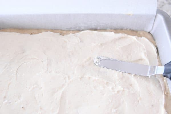 Spreading cream cheese filling into an even layer on top of cake batter.