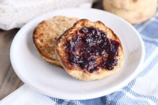 split open easy homemade english muffin with butter and jam on white plate