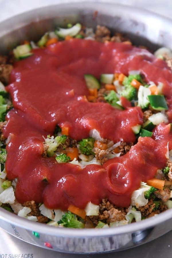 Adding tomato sauce to taco filling.