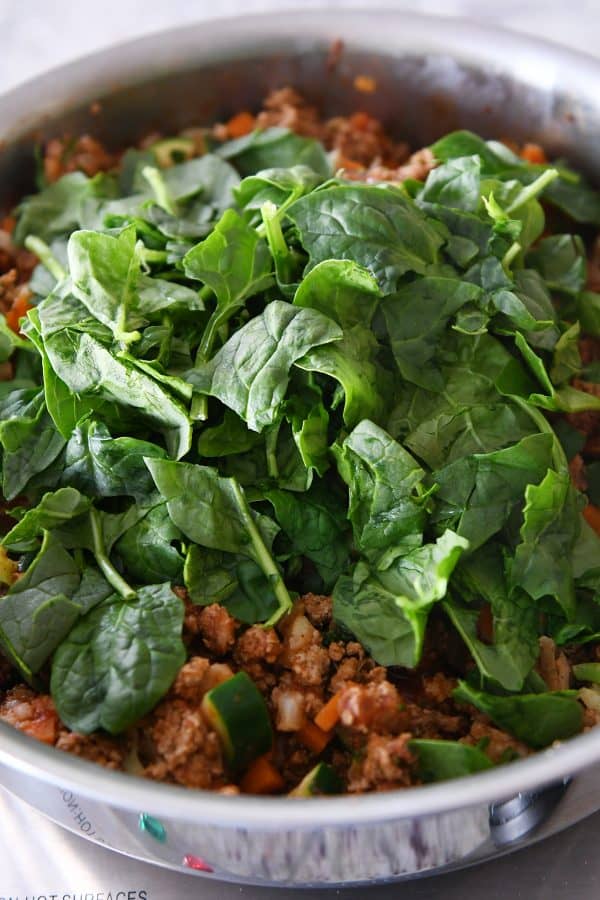Adding spinach to veggie turkey taco lettuce wrap filling.