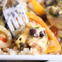 taking bite of cheesy chicken enchilada bake and brown rice