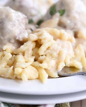 white plate with homemade German spaetzle noodles and meatballs and fork