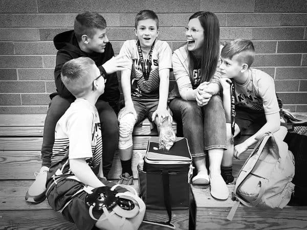 mom sitting in bleachers talking to her kids