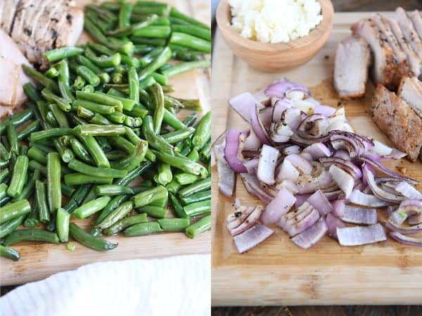 Grilled green beans and grilled onions chopped on cutting board.
