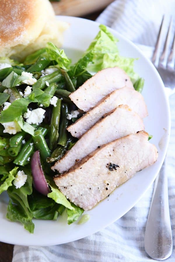 Slices of tender, juicy grilled pork on white plate.