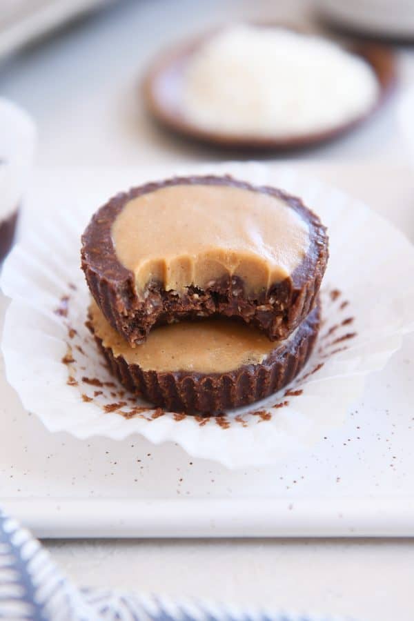Two unwrapped no-bake peanut butter cups stacked with bite taken out of top PB cup.