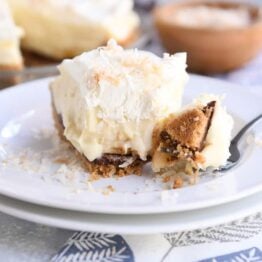bite taken out of banana coconut cream pie on white plate with fork