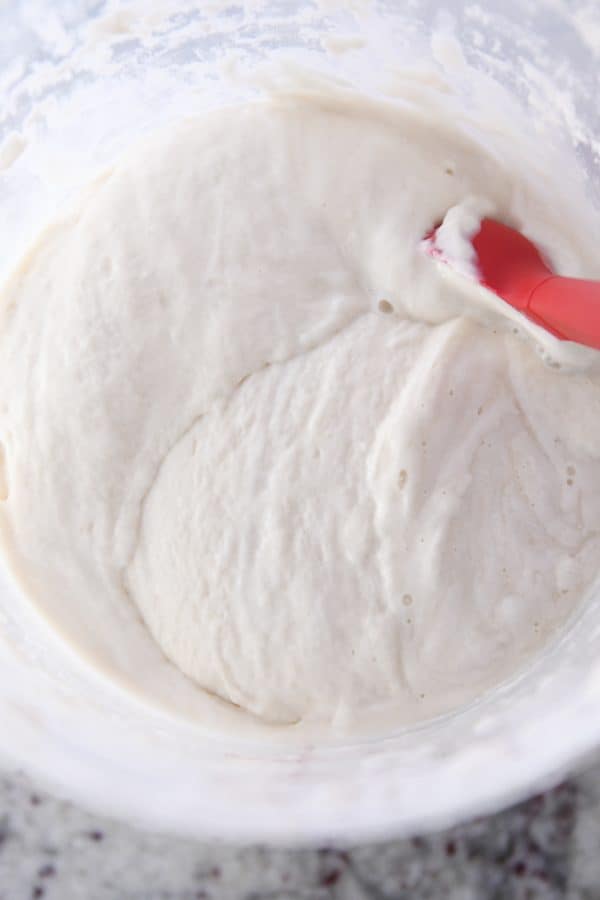 Stirring sourdough starter with red spatula.