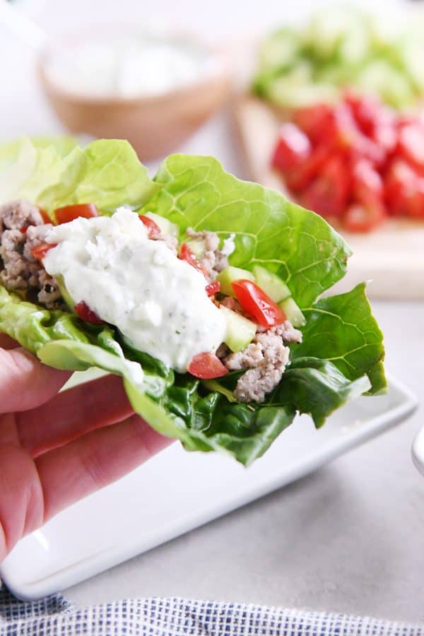 Holding greek lettuce wrap.