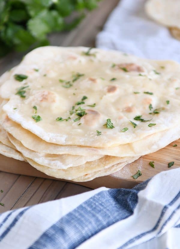 Stack of cooked yogurt flatbreads on wood cutting board.